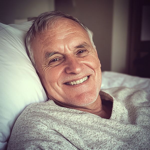 A smiling old man lying in bed